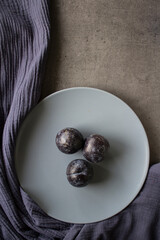 Plums on grey plate. Top view photo of fresh garden fruits. Simple still life. 