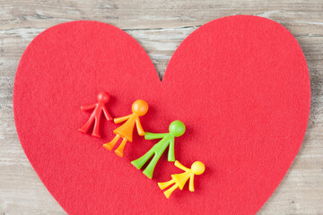 Love concept. Multicolored plastic family figurines are located on a large red heart