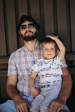 handsome caucasian bearded man in sunglasses and hat with his little 3 year old son. Image with selective focus