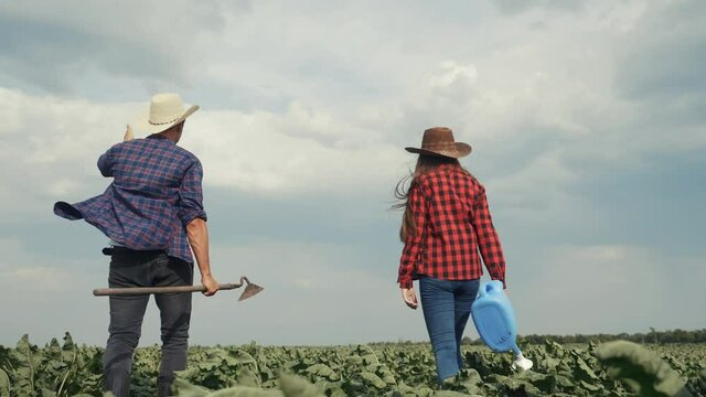agriculture. two farmers in a rubber boots walks green field grass in field. workers farmers goes home after harvesting working crop day agriculture. agribusiness subsistence agriculture