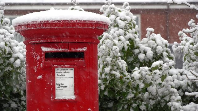A Red post box in the falling snow at Christmas	
