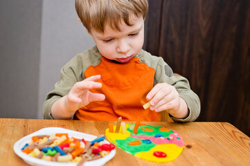 Easter concept. the child places colored noodles on an egg-shaped plasticine. children DIY toys for home ideas, child employment, fine motor skills, ergotherapy, sensory therapy