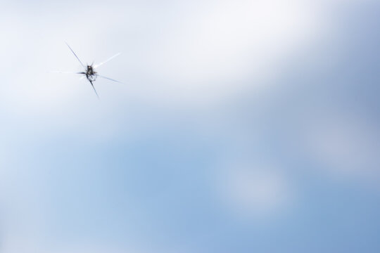 Broken windshield of a car. A web of radial splits, cracks on the triplex windshield. Broken car windshield.