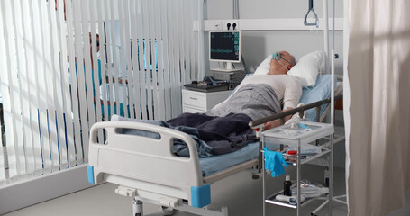 Elderly person with oxygen mask lying in hospital bed