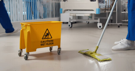 Close up of janitor washing floor with mop and bucket in hospital ward