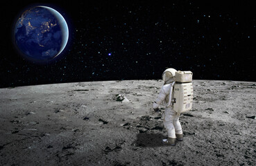 An astronaut standing on the surface of the moon looking up to the earth on the background....