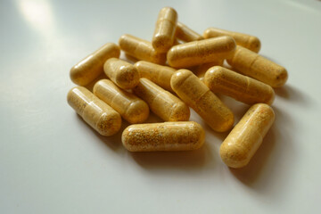 Closeup of handful of orange cellulose capsules of multivitamins