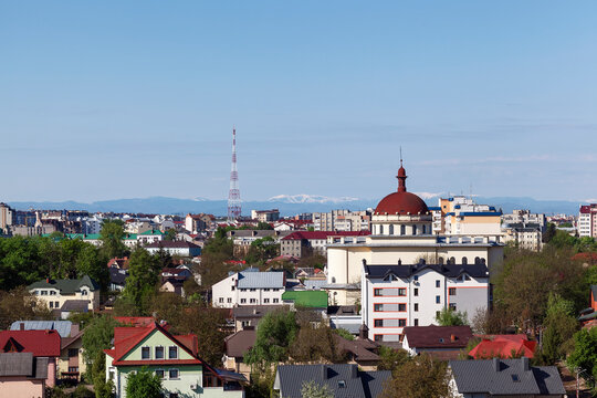 Top View Of Spring City With Church. City On A Background Of Snowy Mountains In The Distance