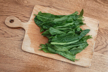 Green sorrel leaves on a wooden board. The greens are prepared for cutting.