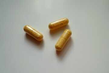 Close shot of three orange cellulose capsules of multivitamins