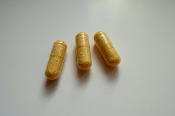 Group of three orange cellulose capsules of multivitamins