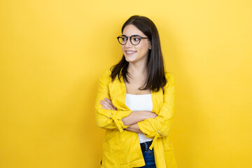 Young brunette businesswoman wearing yellow blazer over yellow background looking to side, relax...
