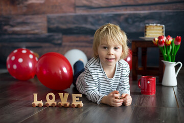 Fototapeta na wymiar Cute toddler blond child, cute boy with valentine decoration, love, flowers, cake