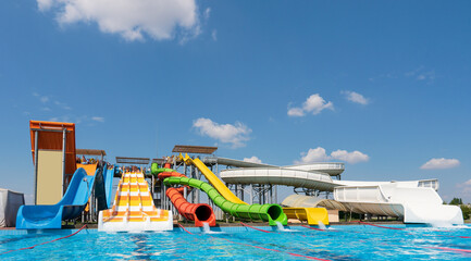 Fototapeta na wymiar Water park, bright multi-colored slides with a pool. A water park without people on a summer day