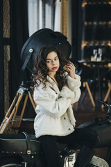 Fototapeta na wymiar girl in a white fur coat on a motorcycle