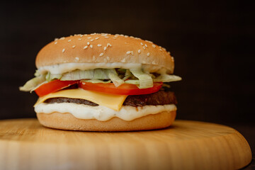 burger with cheese and tomato on a wooden plank