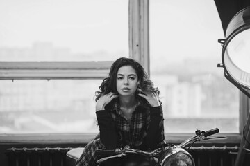Plakat girl in a plaid shirt near a motorcycle in the garage