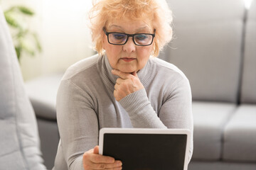 Fototapeta premium elegant middle aged woman using tablet pc at home