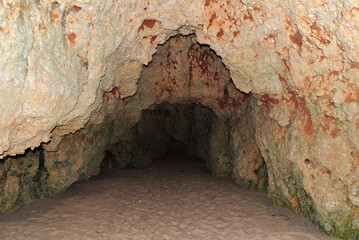 Obraz premium Close Up of Small Cave in Rocky Cliff on Sandy Beach 