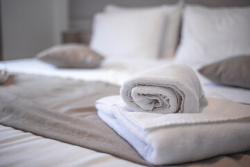 Fototapeta na wymiar Clean towels on bed at hotel room. Bed maid-up with clean white pillows and bed sheets in beauty bedroom. Close-up. interior background. Towel in Hotel Room , Welcome guests , Room service