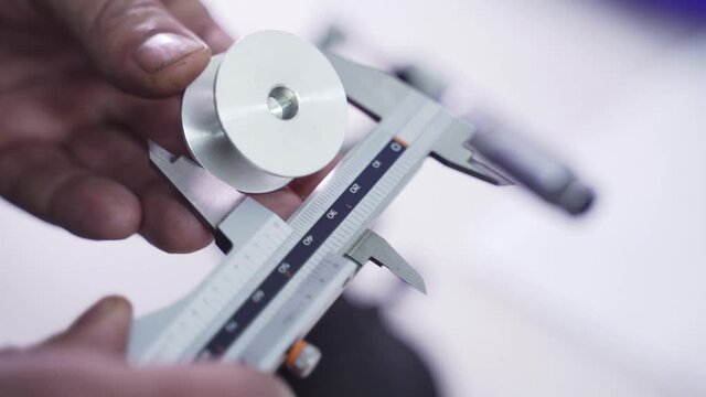 Measuring metal piece with vernier caliper. Worker conducts defect diagnosis of parts in production