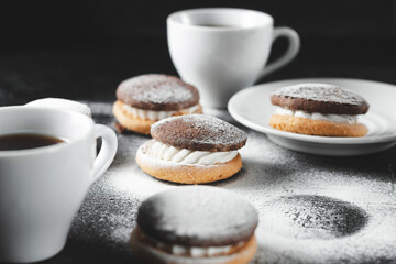 Fresh pastries, pastries from the bakery with white cups of coffee on a dark background