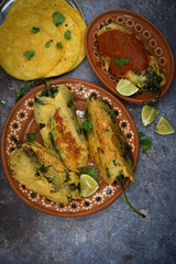 Mexican chiles rellenos stuffed with potato and cheese, vegan batter, served in traditional clay dish