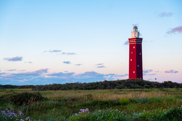 Fototapeta na wymiar Lighthouse standing on the Dutch coast with a dramatic. and colorful dusk or dawn sky behind it. High quality photo