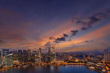 Singapore downtown skyline at sunset. Dramatic twilight sky above financial district waterfront buildings.