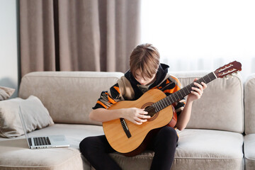 Boy playing guitar at home, online lesson. High quality video