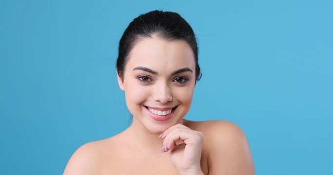 Beautiful woman with naked shoulder touching her chin and flirting by winking eye
