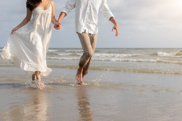 Close up couple holding hands walking on beach. Romantic beach vacation.