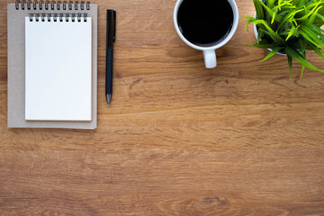 Top view of open school notebook with blank pages, coffee cup and pen for taking write notes on table background. Flat lay, creative workspace office. Business-education concept with copy space.