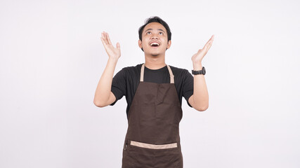 The man wearing the apron stands on a white background pointing up