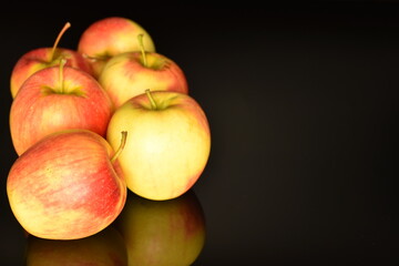 Several ripe organic, juicy, fragrant apples, close-up, on a black background.