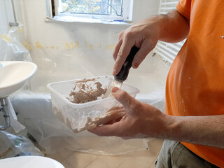 craftsman mixes the material for his work in a bathroom