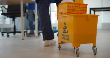 Close up of cleaning service employee pushing cart working in office