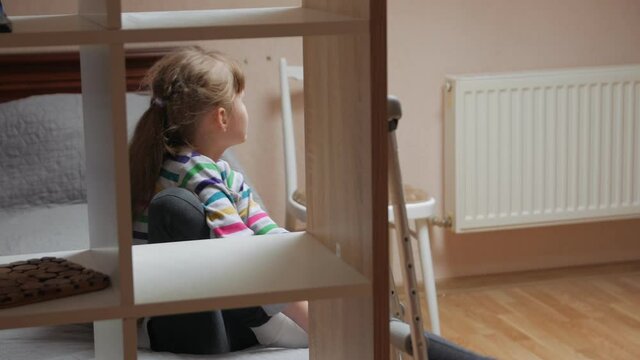 The crutches child girl with plaster on injured leg on the bed