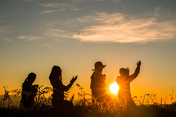 four girl bowed and prayed at sunset in the mountains