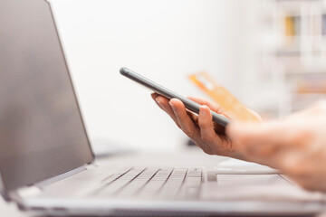 Close up view of hands with phone and credit card. Online purchase from home. Credit card payment.