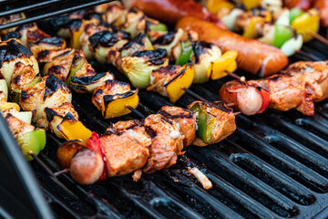 assorted delicious grilled meat with vegetables and sausages on barbecue grill, close up
