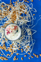 Handmade ecofriendly candle on a blue background. Soya wax healthy candle with dried flowers. Natural material for aroma candles. Top view on scented flavored candle for home interior design.