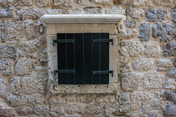 Fototapeta na wymiar Closed black window shutters in a stonewall surround. Kotor, Montenegro.