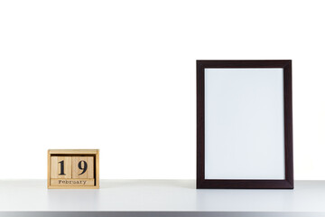 Wooden calendar 19 february with frame for photo on white table and background