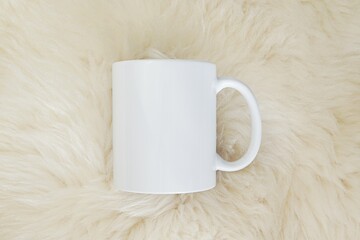 White blank coffee mug mockup for design presentation, fur rug.