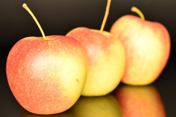 Three ripe organic, juicy, fragrant apples, close-up, on a black background.