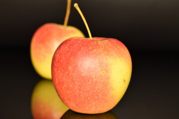 Two ripe organic, juicy, fragrant apples, close-up, on a black background.