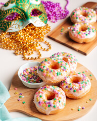 Mardi gras carnival sprinkled doughnuts and beads, holiday celebration, baking, top view