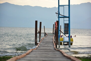 Wooden pier on Lake Shkodra in Albania in the sunset with a view of the mountains of Montenegro