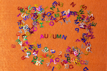 Bright multicolored small letters scattered autumn on an orange background